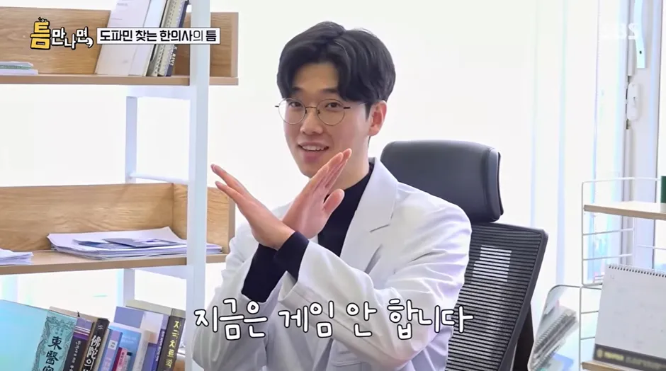 의사 가운을 입은 남성이 "지금은 게임 안 합니다" 문구가 적힌 팻말을 들고 있는 모습