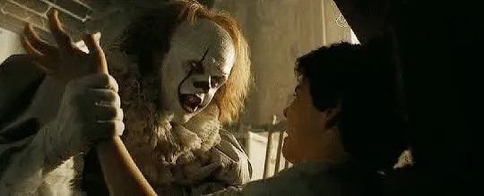 공포영화 '잇'의 페니와이즈 광대가 이빨을 드러내며 위협하는 장면