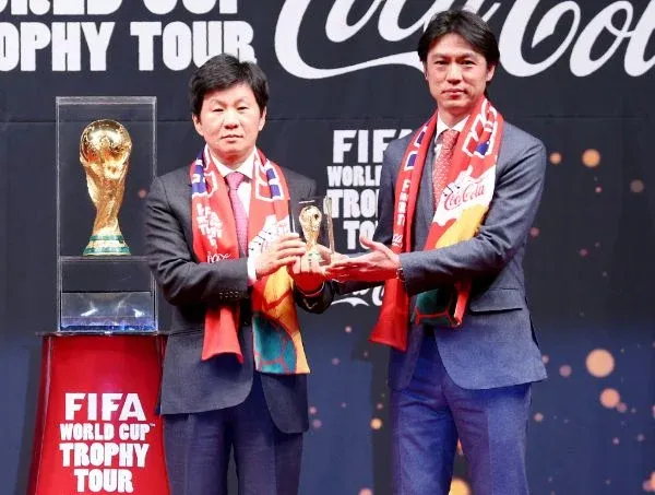 FIFA 월드컵 트로피를 들고 있는 손과 현금 100만원 다발