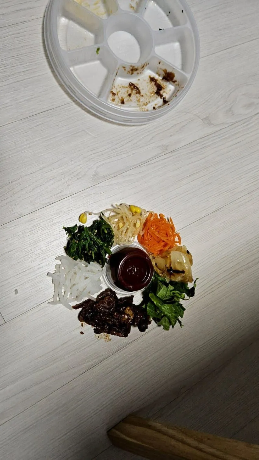 바닥에 엎질러진 비빔밥을 먹고 있는 고양이