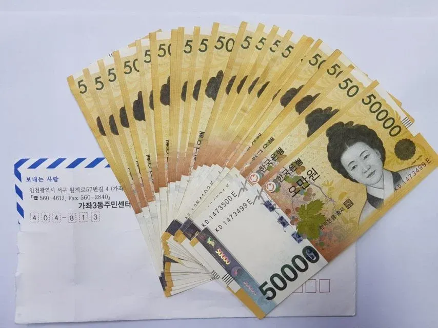 현금 오만원권 두 장과 우편물 봉투가 놓인 사진