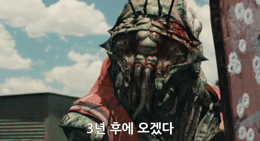 "3년 후에 오겠다"라는 자막이 표시된 영화 디스트릭트9의 외계인 장면
