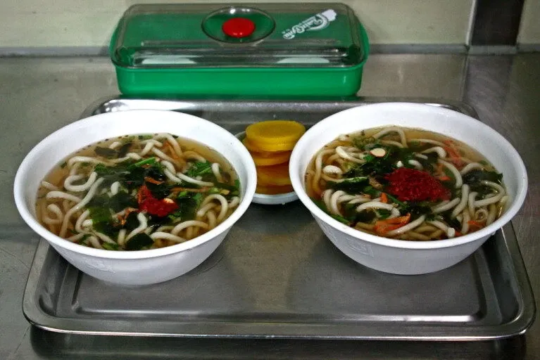 기차역 플랫폼에서 우동을 먹는 승객들의 흑백 사진