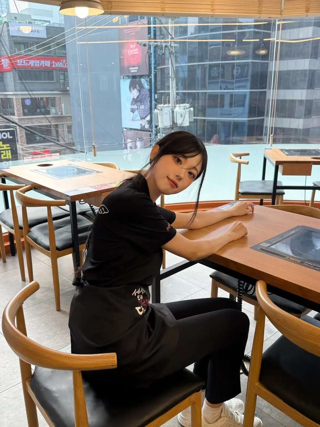 떡볶이집에서 일하는 알바생이 '세상의 모든 떡볶이' 문구 앞에 서 있는 모습