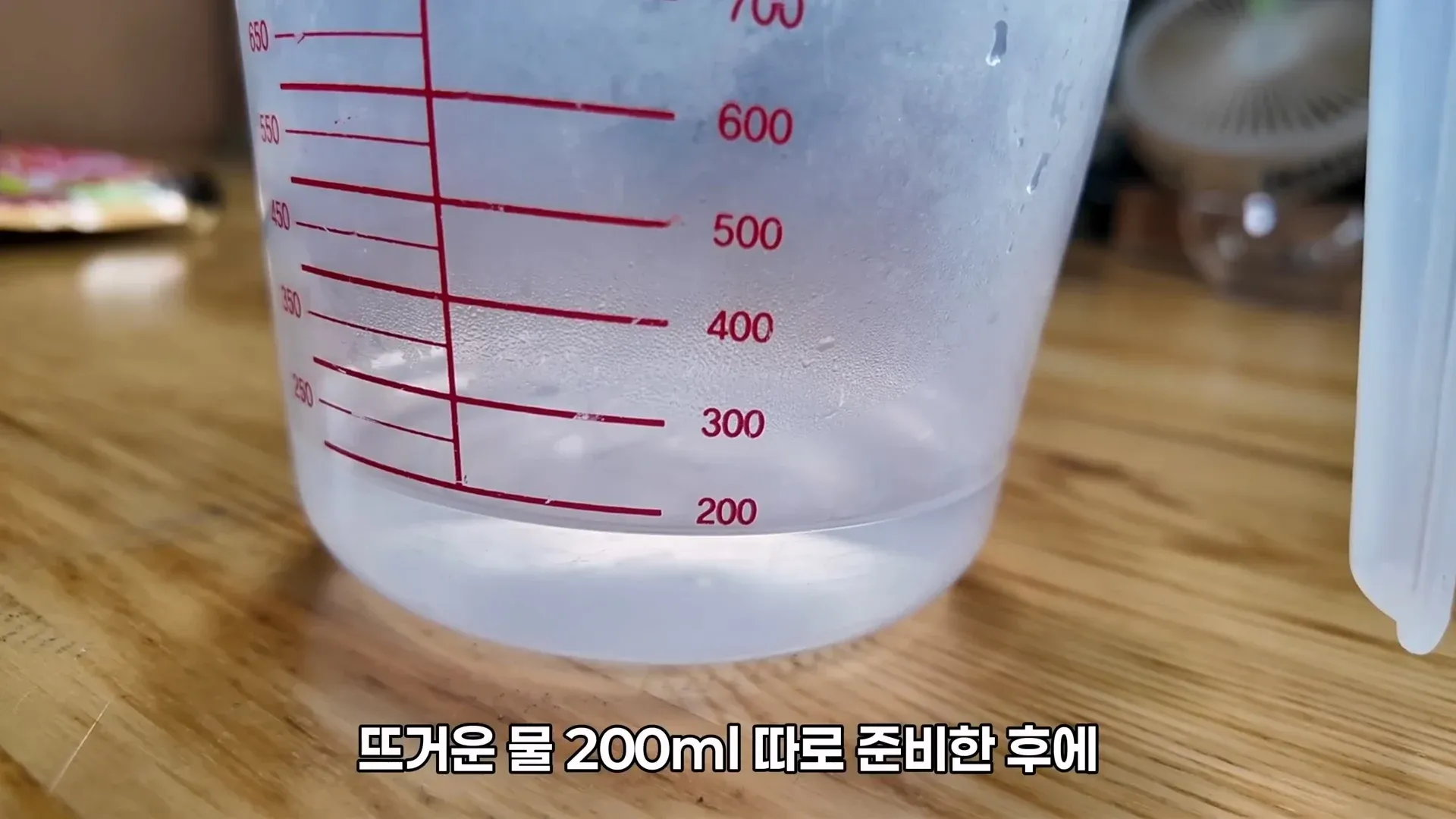 뜨거운 물 200ml을 재는 냉면 육수 조리 단계