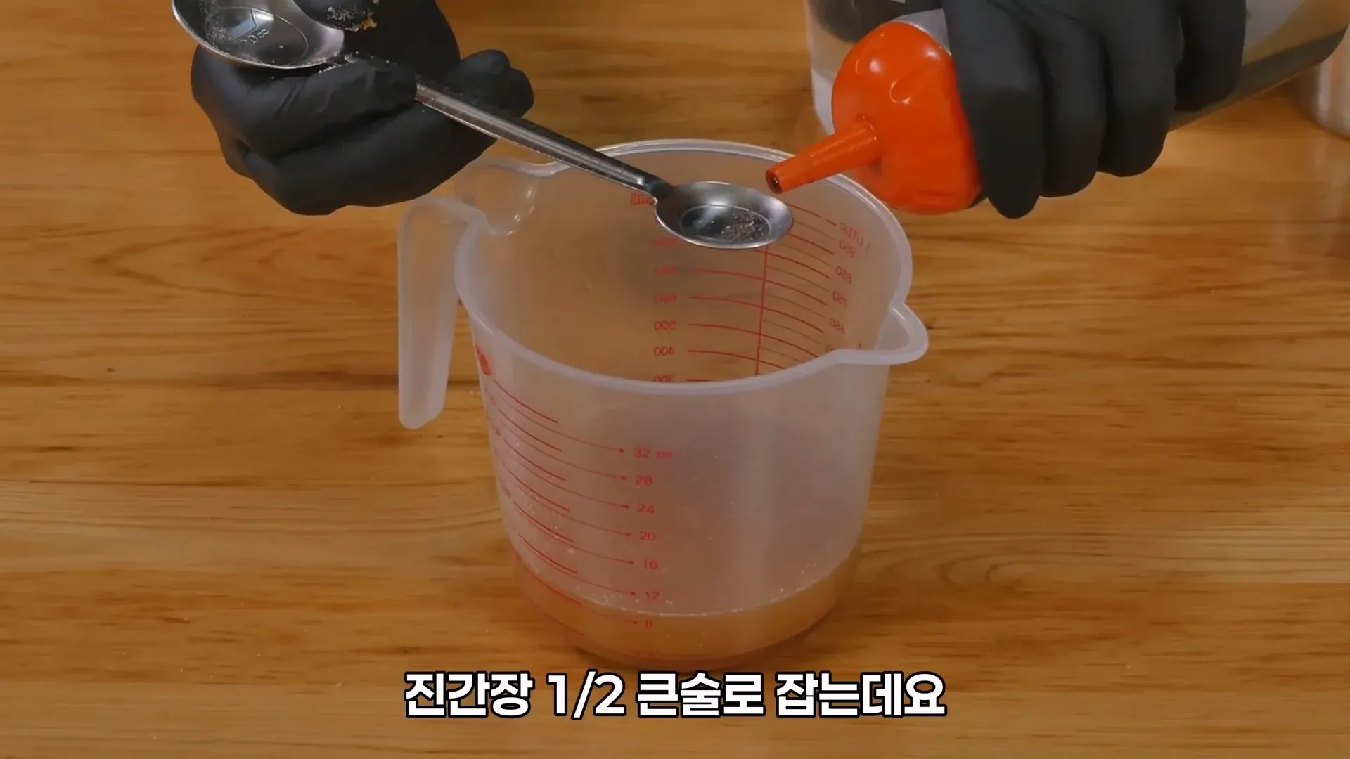 냉면 육수에 진간장 1/2 큰술을 넣고 있는 요리 장면
