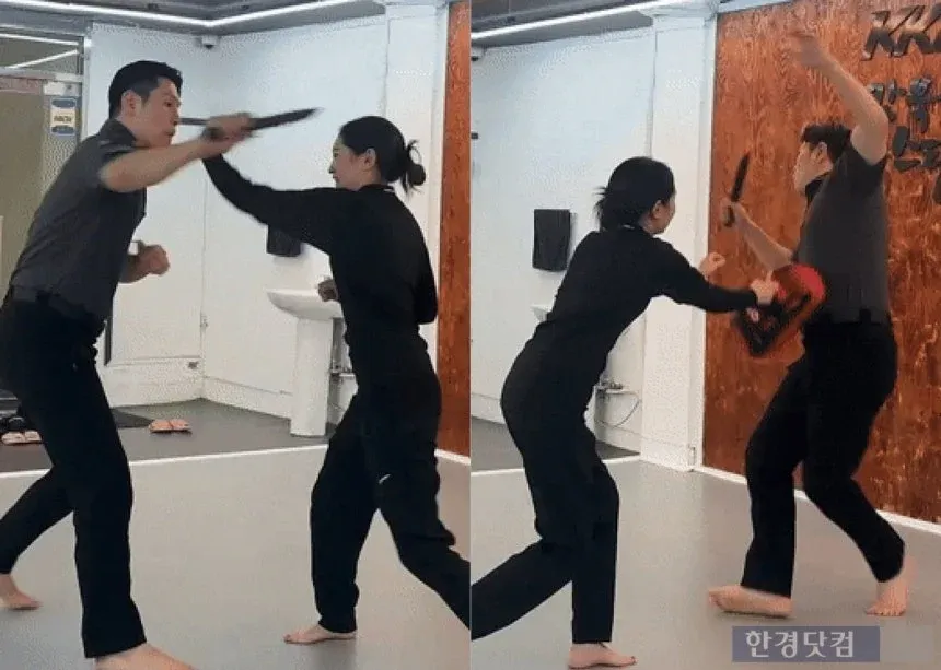복싱 글러브를 낀 20대 여성이 체육관에서 샌드백을 치고 있다.