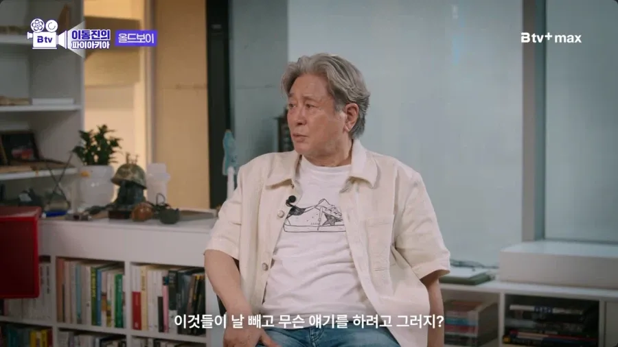 촬영장에서 동료들이 등을 돌린 채 대화하고, 배우가 홀로 서 있다