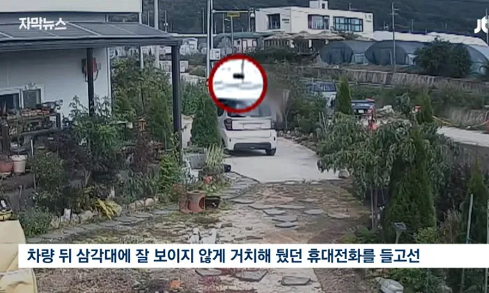 차량 뒤 삼각대에 숨겨 둔 휴대전화를 들고 있는 모습